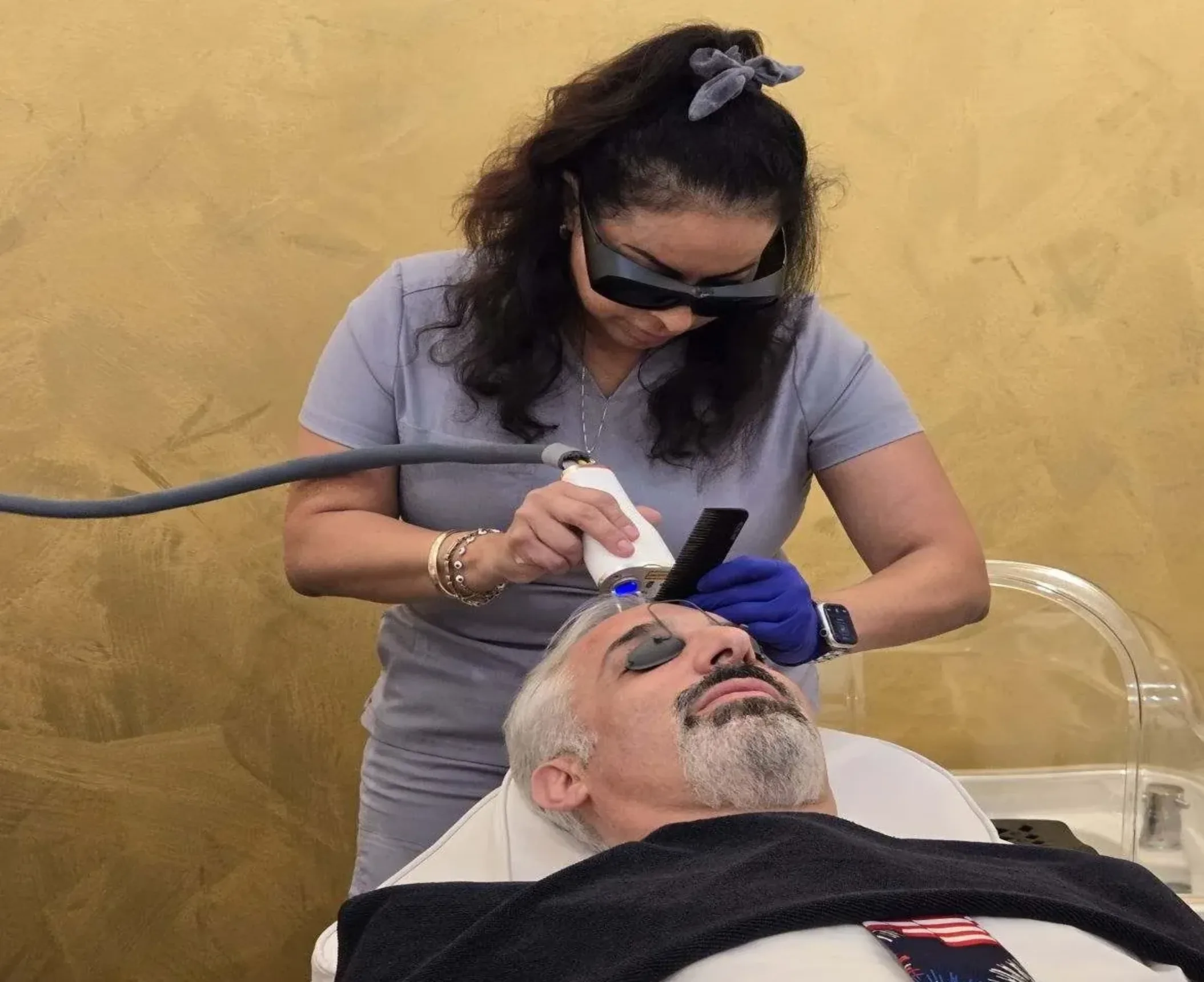 A healthcare professional performs a treatment on a patient lying down, with modern equipment in a serene, gold-toned environment A healthcare professional performs a treatment on a patient lying down, with modern equipment in a serene, gold-toned environment