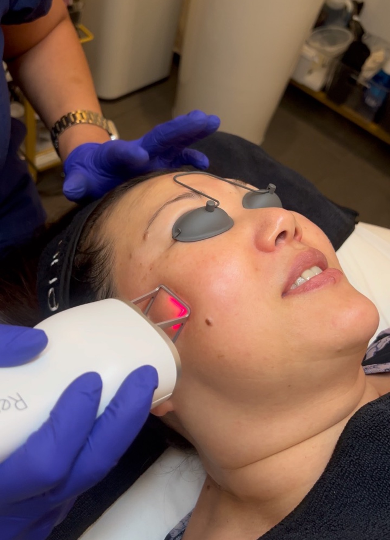 A healthcare professional performs a treatment on a patient lying down, with modern equipment in a serene, gold-toned environment